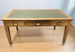 A 1920's oak three drawer writing table with faux leather inset top,