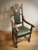 A reproduction carved oak and studded green leather high backed armchair,