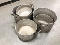 A group of twin handled aluminium cooking pots,
