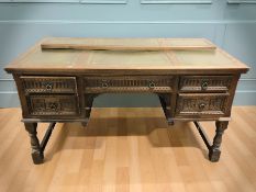 A reproduction carved oak five drawer twin pedestal writing desk with tooled leather inset surface,