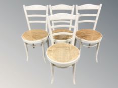 A set of four painted and caned ladder back chairs.