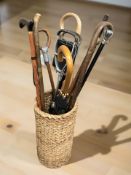 A wicker stick stand containing walking sticks, shooting stick,
