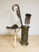 A brass stick pot containing two shooting sticks, walking stick and a small collapsible stool.
