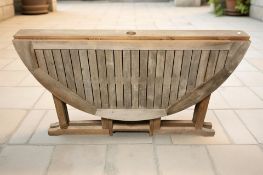 A teak drop leaf garden table, width 114 cm.