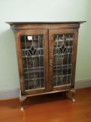 An Art Nouveau oak, stained and leaded glass double door bookcase on pad feet,