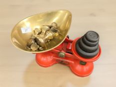 A set of red painted metal scales with brass and cast metal weights