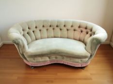 A late Victorian kidney shaped two-seater settee, in buttoned upholstery,