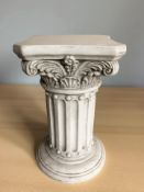 A resin plant stand in the form of a classical column,