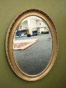 An oval gilt and bevelled mirror,