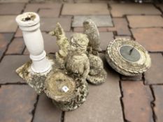 A group of weathered concrete garden statues, bird bath,