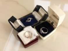 Two silver dress rings with amethyst coloured stones and a further dress ring