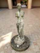 A weathered concrete statue of the Venus Di Milo on plinth,