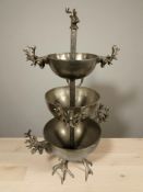 A metal three tier stand decorated with stags heads, height 84 cm.