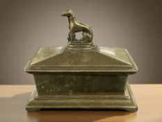 A Victorian brass sarcophagus snuff box surmounted by a seated dog, width 12 cm.