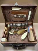 A good quality travelling dressing set including six silver topped bottles/jars in leather suitcase