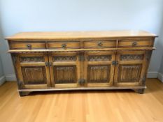 A reproduction oak linen fold sideboard, retailed by Barkers of Northallerton,