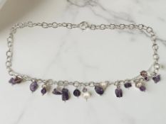 A silver necklace strung with amethysts and freshwater pearls,