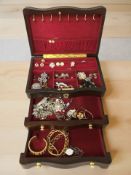 A modern jewellery box containing costume jewellery including various brooches and earrings,