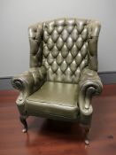 A reproduction deep buttoned olive green chesterfield wingback armchair, width 85 cm.
