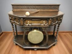 An early 20th century carved oak dining room side table incorporating a brass dinner gong beneath,