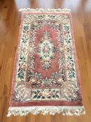 A Chinese woolen rug on salmon ground, 181 cm x 93 cm.
