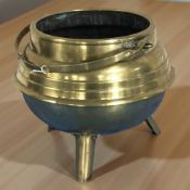 A brass swing handled cauldron on tripod feet, diameter 32 cm.