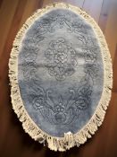 A Chinese oval woolen rug on blue ground, 173 cm x 106 cm.