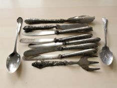 Two silver spoons and a group of silver handled knives and other cutlery.