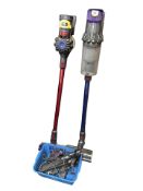Two Dyson stick vacuum cleaners.