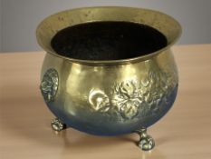 An embossed brass planter with lion mask handles, on claw and ball feet, diameter 28 cm.
