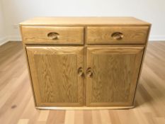 An Ercol elm side cabinet fitted with cupboards and drawers,