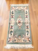 A Chinese woolen rug on green ground, 137 cm x 61 cm.