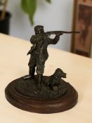 A small patinated metal figure of a shooter with gun dog, on wooden plinth, height 13 cm.