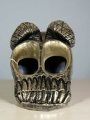 A silvered composition hand ornament in the form of a ram's skull.