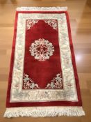 A Chinese woolen rug on red ground, 171 cm x 89 cm.