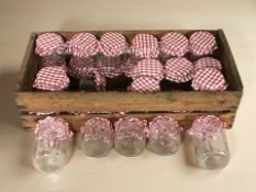 A collection of Kilner glass preserve jars contained in a rustic pine box.