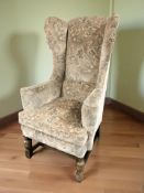 A 20th century oak framed wing back armchair in floral upholstery.