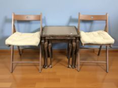 A reproduction mahogany nest of three tables and a pair of folding wooden chairs.