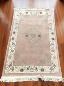 A Chinese woolen rug on pink ground, 199 cm x 120 cm.
