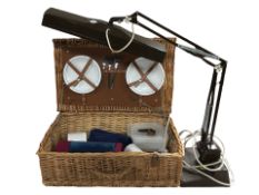 A wicker picnic hamper and an angle poise lamp.