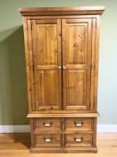 A modern pine double door wardrobe with hanging space to interior and fitted four drawers beneath,