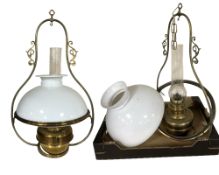 A pair of brass hanging oil lamps with opaque shades and clear glass chimneys, each 70 cm high.