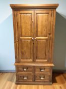 A modern pine double door wardrobe with hanging space to interior and fitted four drawers beneath,