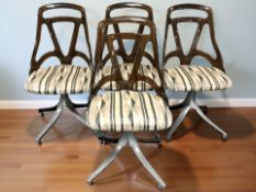 A set of four moulded plastic swivel dining chairs on chrome supports.