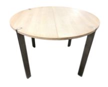 A contemporary circular oak extending table with internal leaf on chrome legs,