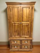 A modern pine double door wardrobe with hanging space to interior and fitted four drawers beneath,