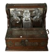 A brass mounted oak Tantalus with three decanters, width 36 cm.