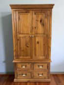 A modern pine double door wardrobe with hanging space to interior and fitted four drawers beneath,