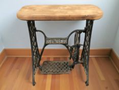 A Singer cast iron treadle sewing machine base with later pine top, width 77 cm.