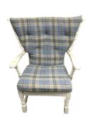 A painted wooden armchair with tartan cushions.